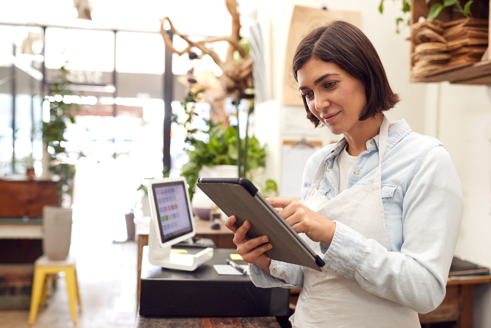 Female,Owner,With,Digital,Tablet,Standing,Behind,Sales,Desk,Of